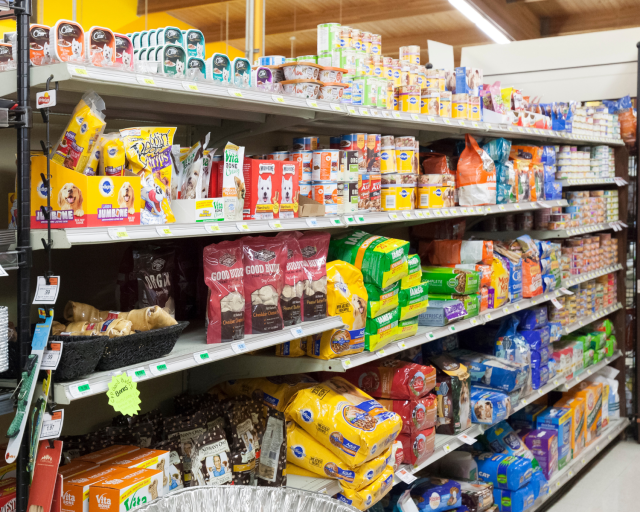 Pet food aisle at Peggy Adams Animal Shelter with various brands and types of dog and cat food.